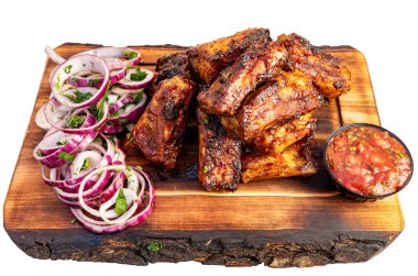 Izgara pirzola, dilimlenmiş soğan ve bir kase salsa sosunun yanında ahşap bir tahtanın üzerinde. Bu yemek bir restoranda servis edilir..