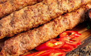 Akşam üstü yapılan sıradan bir toplantıda kebaplar kırmızı biber dilimlerinin yanında ahşap bir tahtanın üzerinde cızırdıyor..