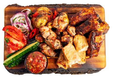 Büyük bir ızgara et servisi ahşap bir tahtanın üzerinde düzenlenir. Taze sebzeler etin yanına konur. İçinde sos da var..