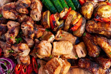 Yazın güneşli bir havada ahşap bir tabakta çeşitli ızgara et ve sebze türleri servis edilir..