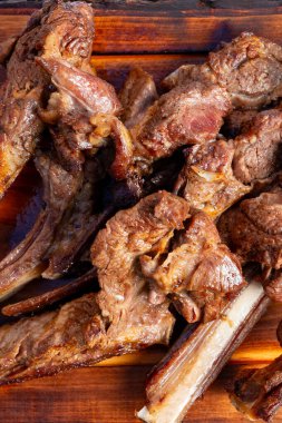 İnsanlar yaz boyunca arka bahçede toplanıp ahşap bir masada ızgara pirzola yiyorlar..