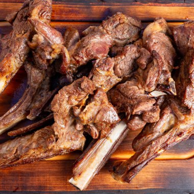 Izgarada pişirildikten sonra tahta bir tahtada sulu kuzu kaburgaları düzenlenir. Bu sahne sosyal bir etkinlikte servis için hazır yiyecekleri gösteriyor..