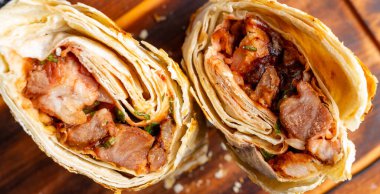 İki paket ikiye bölünmüş, ahşap bir yüzeyde ızgara et ve sebzeler görülüyor. Yemekler lezzetli ve lezzetli görünüyor..