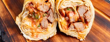 İçinde et, sos ve sebzeler olan bir paket kesiliyor. Mutfaktaki ahşap bir tahtaya konur..