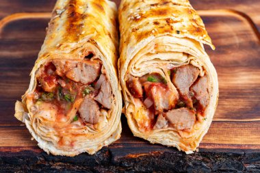 Et ve sosla dolu iki paket ikiye ayrılır ve bir restoran ortamında ahşap bir tahtaya yerleştirilir..