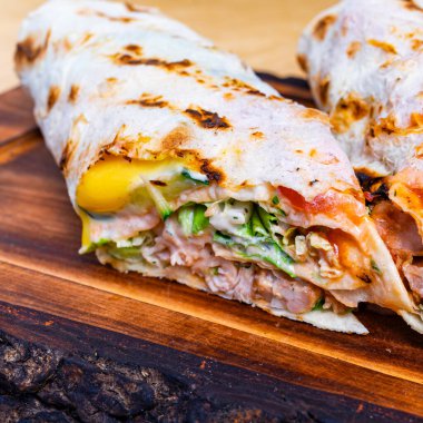 Tahta bir tahta üzerine konmuş tavuk, sebze ve sos katmanlarının ortadan ikiye bölünmüş hali..