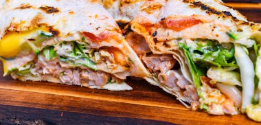 Tavuk, marul, domates ve sosla bir paket taze malzemeler ve sıcak ekmek gösterilerek ikiye bölünür..