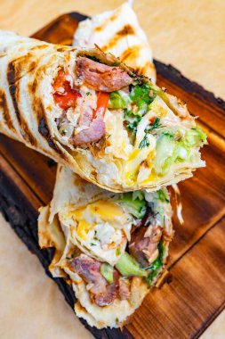 Çeşitli et ve taze sebzelerle dolu bir paket ikiye bölünüyor ve ahşap bir tahtada sergileniyor. Bu yemek hazır..