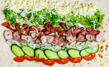 Taze malzemeler mutfaktaki tortilla üzerinde düzenli olarak düzenlenir. Tavuk, sebze ve peynir görülebilir..