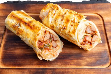 Et ve baharatla dolu iki rulo, mutfaktaki ahşap bir tahtaya konur. Ekmekler altın kahverengiye boyanmış..