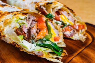 Et, marul, domates ve sos dokusunu göstermek için iki paket kesilmiş. Tahtanın üzerinde dinleniyorlar..