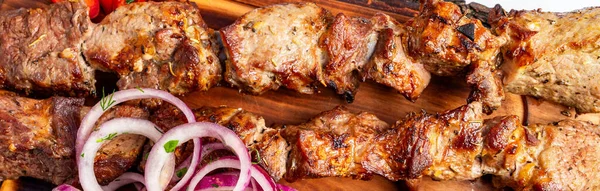 Sulu ızgara et parçaları, yanında dilimlenmiş soğan ve bitkilerle ahşap bir tahtanın üzerine konur. Gece oldu ve ortam ortak..