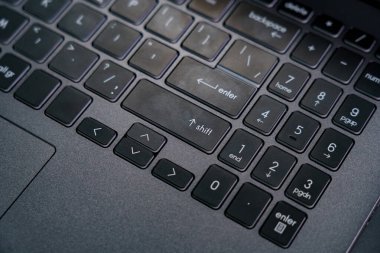 Yakın plan, birisi aygıt üzerinde yazarken giriş ve kaydırma tuşlarına odaklı bir dizüstü bilgisayar klavyesi gösterir.