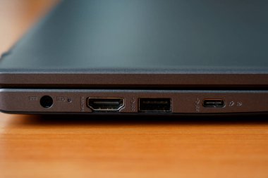 Bağlantı cihazları ve aksesuarları için çeşitli portları gösteren ahşap bir masanın üzerine dizüstü bilgisayar yerleştirilir. Görünüm teknolojiyi vurguluyor.