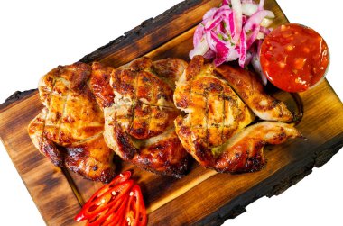 Üç parça ızgara tavuk taze salsa sosu ve dilimlenmiş soğanla birlikte ahşap bir tabakta düzenlenir. Kırmızı biber renk ekler.