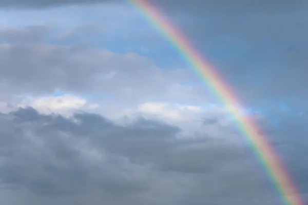 Rainbow formed after a storm when dark clouds begin to part, revealing a blue sky