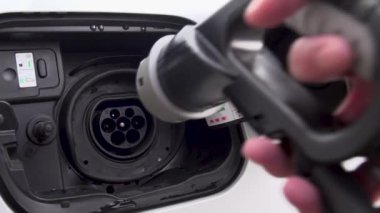 Elektrikli bir arabanın kablosunu takan bir adamın yavaş çekim videosu.