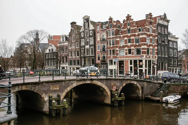 アムステルダム オランダ 2008 アムステルダム市内の運河に架かる橋で 街の典型的な家とボートが曇りと灰色の日にいくつかの階段の横に係留されています — ストック写真