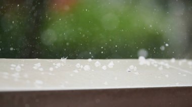 Detail of hail falling on the stone ledge of a terrace during a heavy hail storm during the summer