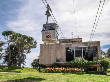 Madrid, İspanya; 06-27-2021: Madrid teleferik kabini Casa de Campo istasyonundan şehre doğru hareket ediyor. Çiçekler ve bitki örtüsüyle çevrili bir bina. Arka planda muhteşem bir gökyüzü var.