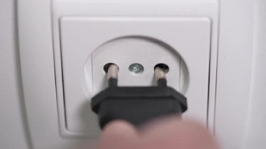 Güç tüketiminin 4K görüntüsü, bir adamın el fişini prize takıp prize taktığı video.