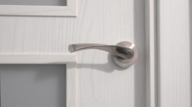 Kafkasyalı bir adamın, kapı tokmağını tutarken, kapıyı açarken, içeri girerken ve arkasından kapatırken.