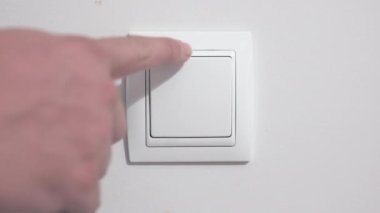 Güç tüketiminin 4K görüntüsü, bir adamın duvar düğmesini açıp kapama videosu.