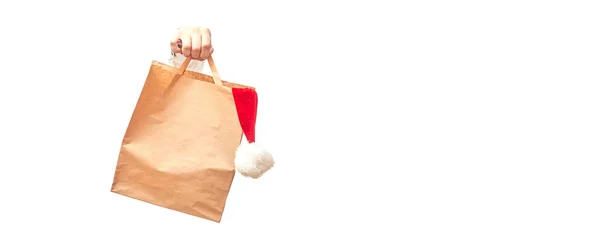 Hand Hält Basteltasche Mit Weihnachtsmütze Auf Weißem Hintergrund Isolieren Banner — Stockfoto