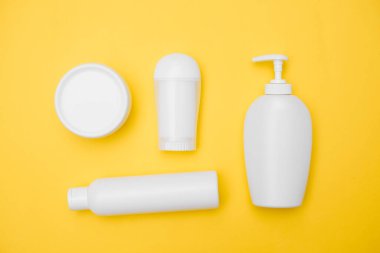 Kişisel hijyen ürünleri. Sarı arka planda beyaz kavanozlar. Kopya alanı, üst görünüm.