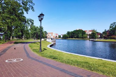 Yukarı Göl 'ün rıhtımında yaya kaldırımı ve yeşil çimen - yapay şehir havuzu, ünlü turistik eğlence ve tatil bölgesi Kalininingrad, Rusya' da güneşli yaz günü
