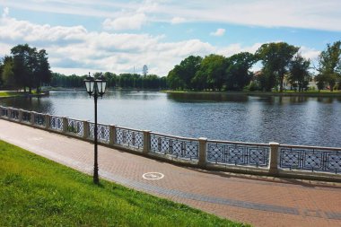 Yukarı Göl seti etrafındaki boş yaya kaldırımı ve yeşil çimenler - yapay şehir havuzu, Kaliningrad, Rusya 'da popüler dinlenme alanı güneşli yaz günü