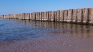 Baltık Denizi kıyısındaki eski ahşap dalgaların alçak açılı görüntüsü yaz günü boş kumsalda dalgalanan sakin dalgalar. Hiçbir insan deniz manzarası doğal değildir..