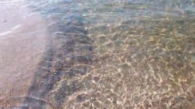 Güneşli yaz gününde, Baltık kıyılarında kumların sığ kumsallarında yuvarlanan sakin ve berrak su dalgalarını kapatın. İnsansız, sakin deniz manzaralı, doğal bir geçmişi var..