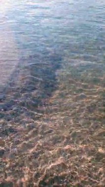 Güneşli yaz gününde Baltık kıyılarındaki boş kumsalın berrak beyaz kumsalında dalgaların yakın çekimi. Hiçbir insan dikey sakin deniz manzarası doğal desen.