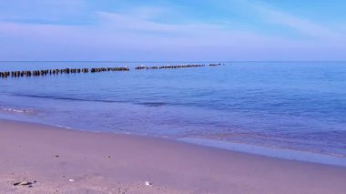 Baltık kıyılarının sakin deniz manzarası boş kumsallarda dalgalar ve açık havada mavi gökyüzünün altında eski ahşap dalgaları. Hiçbir insan doğal deniz manzarasını terk etmez..