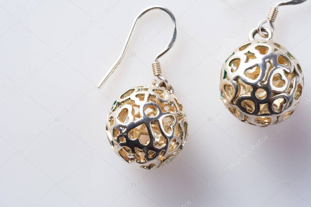Pair of round pearl earrings in the form of balls with hearts on white background. Fashion women's earrings in silver