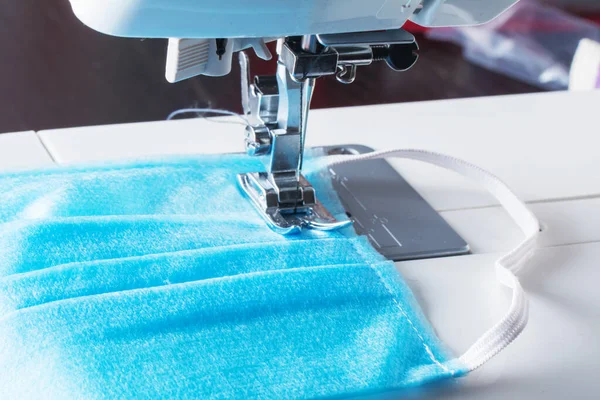 Sewing machine sew home made diy medical reusable protective face mask with sewing machine at home, making cotton fabric medical mask. Coronavirus pandemia Covid-19 virus protection.