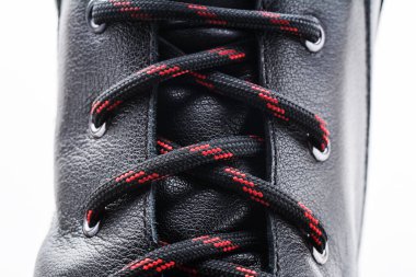 Beyaz arka planda izole edilmiş şık yeni bir ayakkabı. Siyah deri ayakkabı. Kırmızı siyah ayakkabı bağcıkları yakın çekim. Sert deri dokusu.