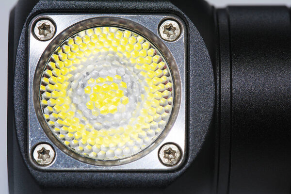 Black metal led headlamp flashlight with a lens close up. Anodized knurled aluminum grip