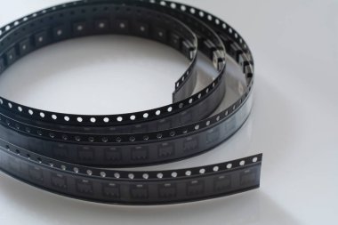 Beyaz arka planda elektronik bileşen. Siyah plastik taşıyıcı bantlı KİS bileşenleri kopyalama alanı ile