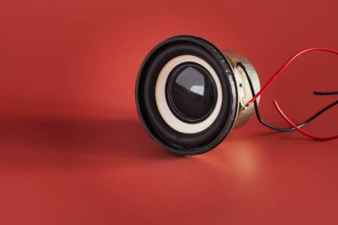 Siyah müzik hoparlörü kırmızı arkaplanda izole edilmiş bir kablo var. Ses ekipmanları.