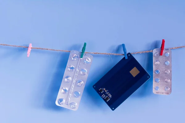 青い背景にプラスチック製のクロッシンツインでぶら下がってデビットカードと空の丸薬水疱 薬の概念と販売 — ストック写真