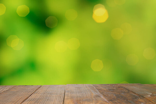 Пустой старый темный деревянный деревенский стол, сделанный из досок с неровными краями на размытом саду и зеленом листе с боке. Используется для отображения или монтажа вашей продукции. Перспективный взгляд. Копирование пространства