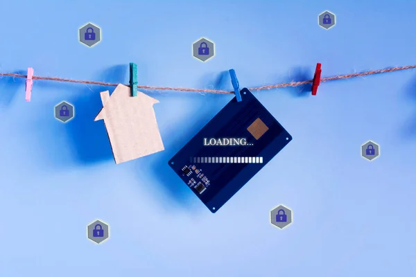Contactless access card and model house hanging with plastic clothespin twine on blue background. Property insurance and security, Real Estate. Protecting smart home from unauthorized access concept