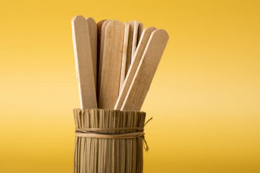 Sarı arka planda bambu vazoda tahta dondurma çubukları. Asgari iş takım çalışması kavramı