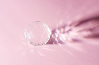 Parlak parlak kristal cam şeffaf top. Pastel pembe arka planda gölgesi var. Asgari değerli yaratıcı konsept