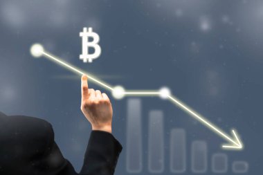İşadamı dijital bitcoin ikonunu işaret ediyor. Çizelge ve diyagram, düşen bitcoin fiyatlarının grafiği. Sanal kripto para birimi borsa konsepti