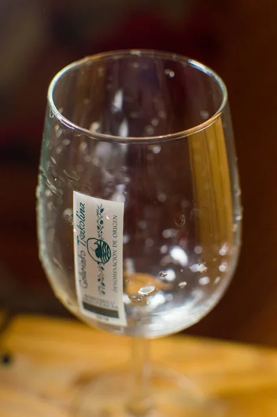 Tahta yüzeyde insan eliyle beyaz şarap kadehi.