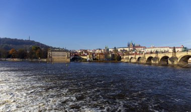 Çek Cumhuriyeti 'nin güneşli bir gününde Vltava Nehri üzerindeki Gotik Kalesi ve Charles Köprüsü ile Sonbahar Renkli Prag Küçük Kasabası