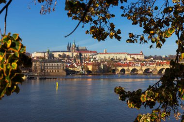 Çek Cumhuriyeti 'nin güneşli bir gününde Vltava Nehri üzerindeki Gotik Kalesi ve Charles Köprüsü ile Sonbahar Renkli Prag Küçük Kasabası